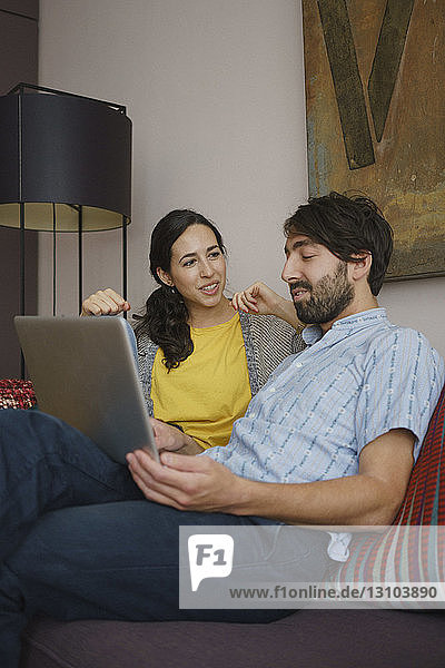Couple using digital tablet on living room sofa
