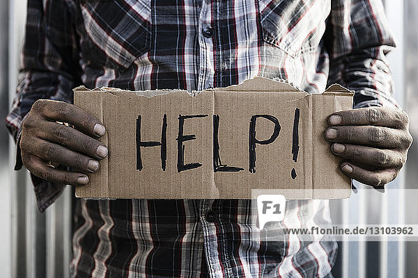 Obdachloser Mann hält Hilfsschild