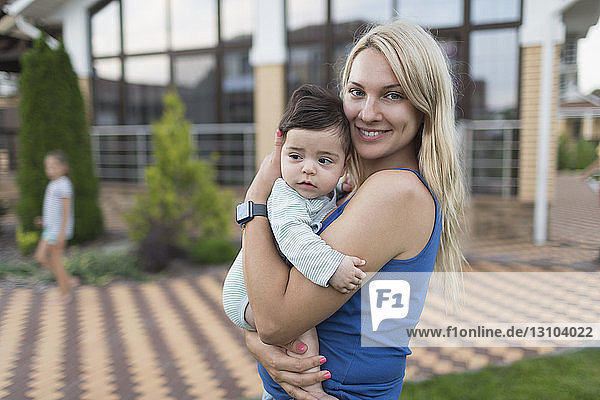 Porträt Mutter hält Baby Sohn im Hinterhof