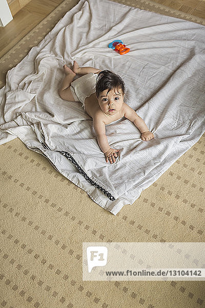 Portrait cute  curious baby boy laying on blanket