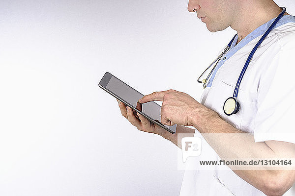 Arzt mit digitalem Tablet vor weißem Hintergrund