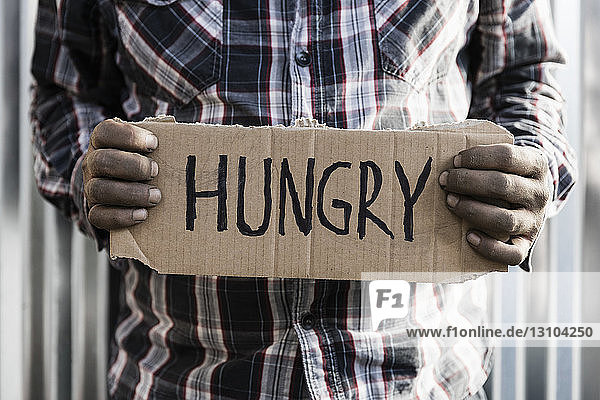 Obdachloser Mann hält hungriges Schild