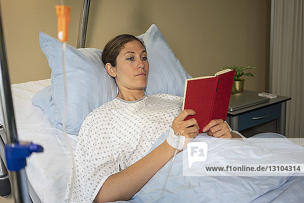 Female patient reading book  resting and recovering in hospital room