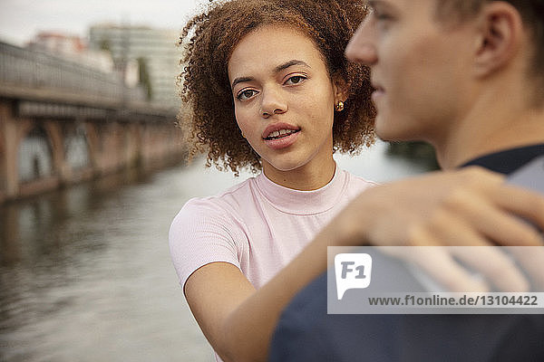 Porträt einer jungen Frau  die ihren Freund am Flussufer umarmt