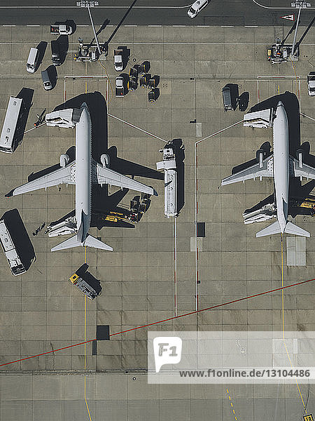 Blick von oben auf Verkehrsflugzeuge  die auf dem Rollfeld eines Flughafens gewartet und vorbereitet werden