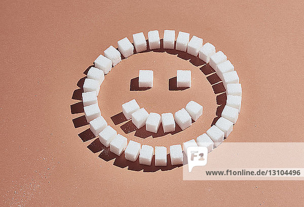 Sugar cubes forming smiley face on peach background