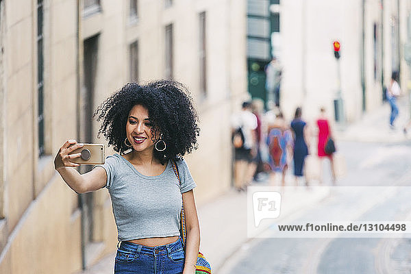 Junge Frau mit Smartphone nimmt Selfie auf städtischen Straße