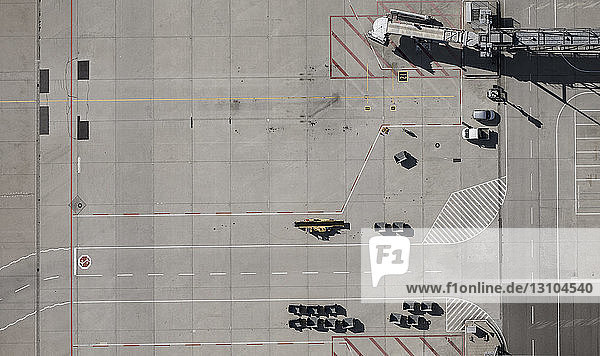 Blick von oben auf Flughafen-Servicefahrzeuge und Fluggastbrücke auf dem Rollfeld des Flughafens