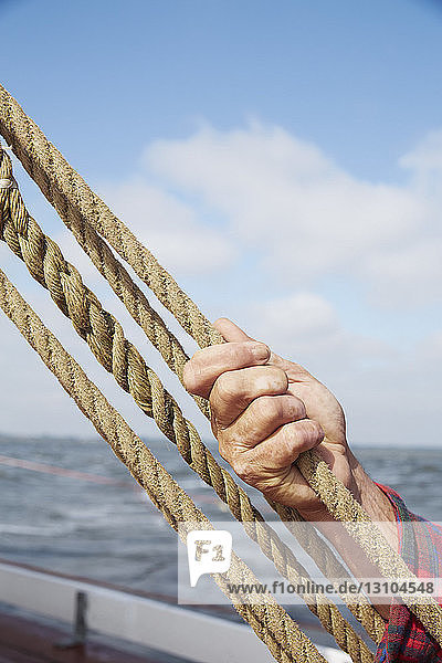 Mann hält ein Seil und stellt die Takelage eines Bootes ein