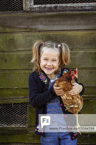 Lächelndes Mädchen hält Hühnchen und schaut in die Kamera.