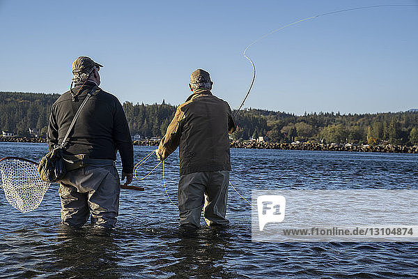 A guide advises his client while fly fishing in salt water for searun coastal cutthroat trout and salmon in northwest Washington State  USA