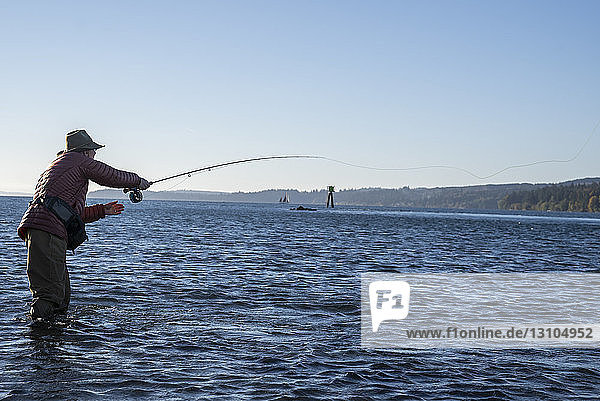 Ein kaukasischer männlicher Fliegenfischer wirft im Salzwasser vor Indian Island im Nordwesten des Bundesstaates Washington  USA  auf Cutthroat-Forelle und Lachs.