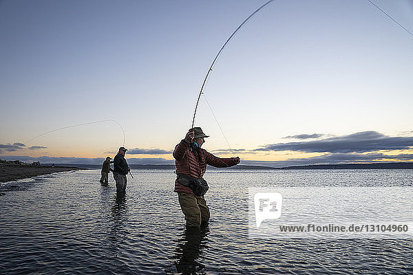 Zwei Fliegenfischer  die an einem Salzwasserstrand an einem Strand an der Westküste der USA mit ihrem Führer zwischen ihnen stehend  nach Searun-Cutthroat-Forellen und Lachsen werfen