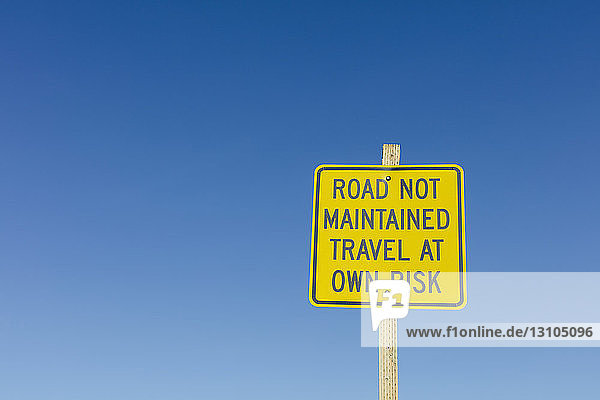 Straße wird nicht unterhalten - Schild Reisen auf eigene Gefahr entlang einer abgelegenen Wüstenstraße