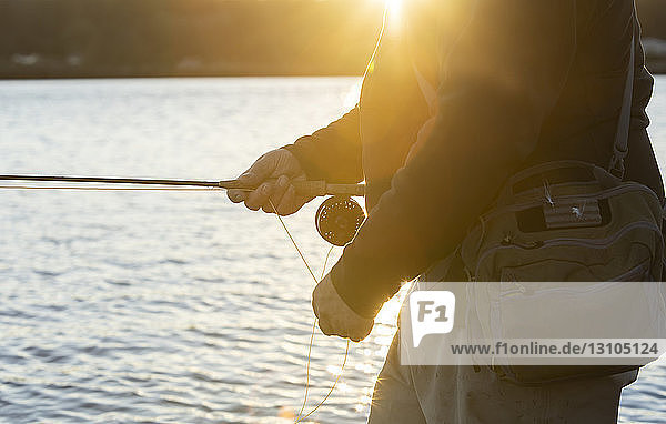 Eine Nahaufnahme der Hände eines Fliegenfischers  der seine Schnur aus einem Wurf herausholt  den er im Salzwasser gemacht hat.