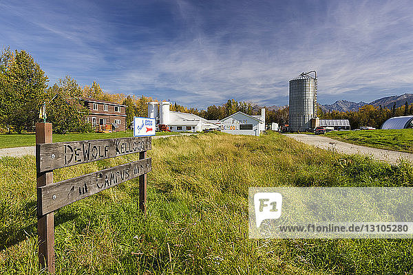 Ein landwirtschaftliches Silo und Nebengebäude stehen im Hintergrund eines Schildes  das die DeWolf Kellogg Farm kennzeichnet  Süd-Zentral-Alaska; Palmer  Alaska  Vereinigte Staaten von Amerika