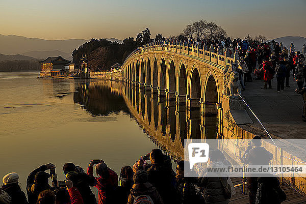 Touristenmenge  die die 17-Bogen-Brücke bei Sonnenuntergang fotografiert  Sommerpalast; Peking  China
