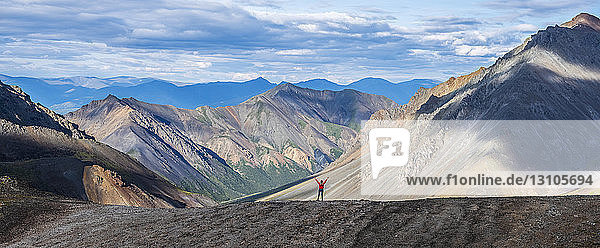 Woman standing with her arm raised while on a ridge line in Kluane National Park and Reserve; Haines Junction  Yukon  Canada