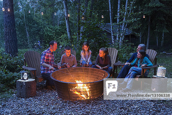 Eine Familie versammelt sich in der Abenddämmerung um ein Lagerfeuer; Salmon Arm  British Columbia  Kanada