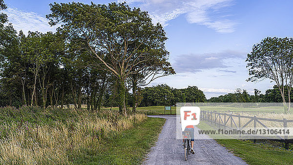 A woman rides her bike down a road at Gleno Abbey Hotel and Golf Course; County Galway Ireland