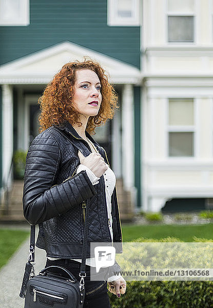 A woman with red  curly hair walking outdoors in a neighbourhood; North Vancouver  British Columbia  Canada