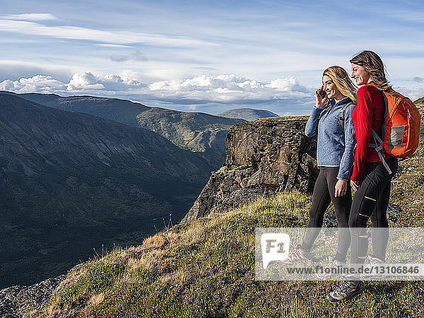 Zwei Frauen benutzen ihre Handys und erkunden die Berge und die Wildnis des Yukon um Haines Junction; Yukon  Kanada