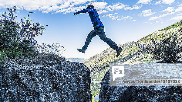 Ein Mann springt über eine Lücke zwischen zwei Felsklippen; Logan  Utah  Vereinigte Staaten von Amerika