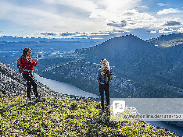 Two women exploring the mountains and wilderness of the Yukon  feeling alive and vibrant in the beautiful scenery around Haines Junction. One friend taking photos of the other one; Yukon  Canada