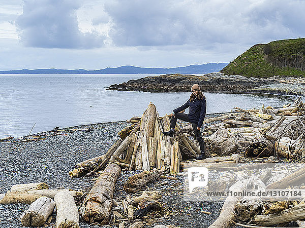 Eine junge Frau steht auf Treibholz am Spiral Beach  Vancouver Island; Victoria  British Columbia  Kanada