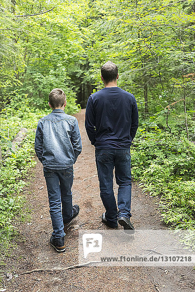 Father and son walking together on a trail; Salmon Arm  British Columbia  Canada