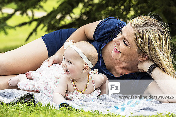 Eine junge Mutter spielt mit ihrem Baby auf einer Decke in einem Stadtpark an einem warmen Sommertag; Edmonton  Alberta  Kanada