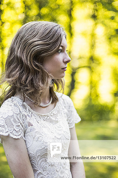 Portrait of a teenage girl in a lace dress standing in a park in autumn; Surrey  British Columbia  Canada