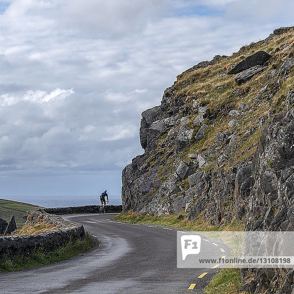 Radfahren auf einer Straße entlang der Küste  Dingle-Halbinsel; Ballyferriter  County Kerry  Irland