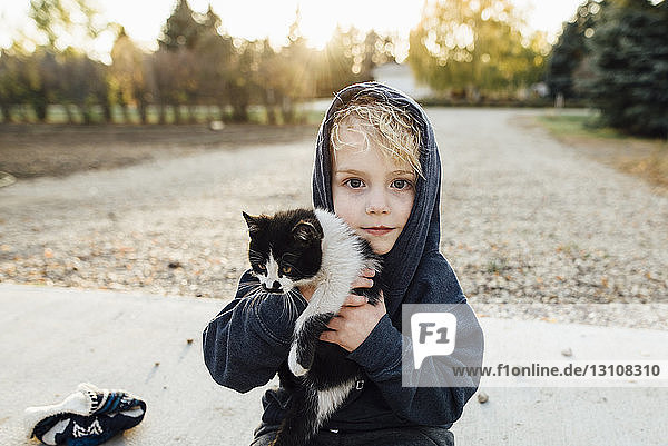 Portrait of cute boy carrying cat at park