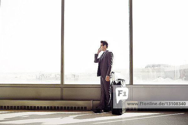 Geschäftsmann antwortet auf Smartphone  während er am Fenster in der U-Bahn-Station steht