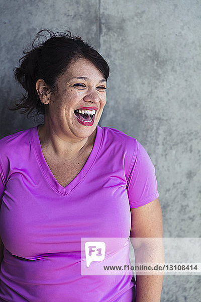 Happy woman looking away while standing against wall in yoga studio