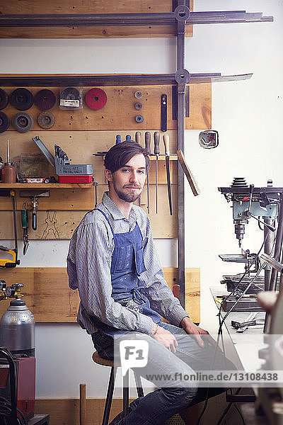 Porträt eines selbstbewussten Arbeiters  der in einem Workshop sitzt