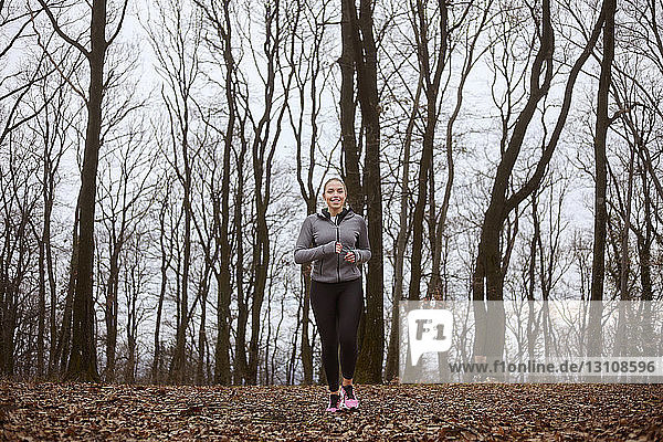 Lächelnde Frau joggt auf dem Feld im Fruska-Gora-Nationalpark