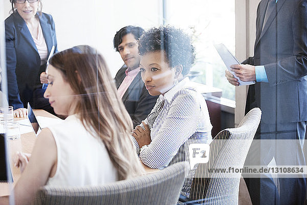 Colleagues looking at businesswoman during meeting in office