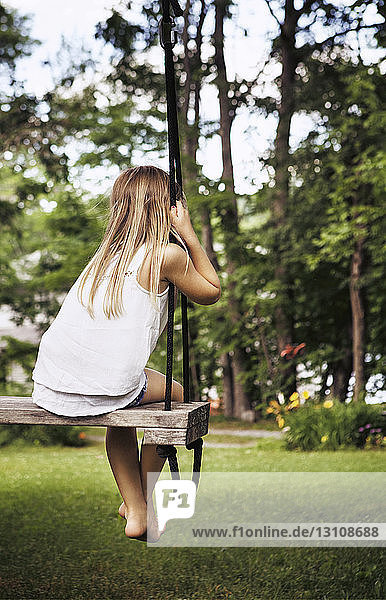 Rear view of girl sitting on swing at park