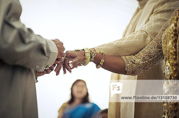 Priester bindet Braut und Bräutigam während der Hochzeitszeremonie die Finger