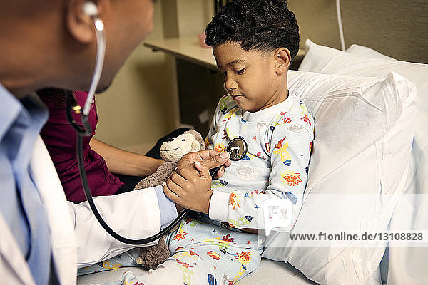 Doctor examining boy on bed in hospital