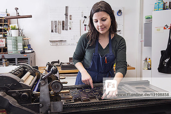 Frau ordnet Alphabete an Maschinen in der Druckerpresse an