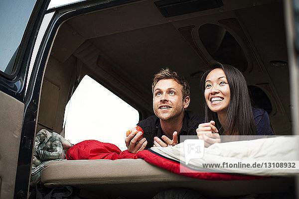 Happy couple lying in back of camping van