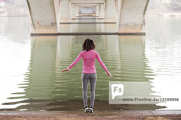 Rückansicht einer Frau  die am Seeufer unterhalb der Lamar-Boulevard-Brücke springt