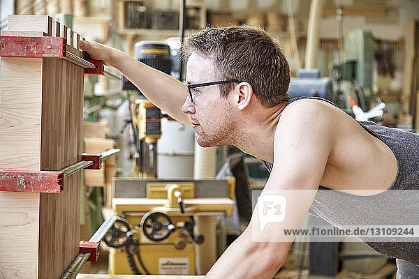 Side view of carpenter examining manufactured object in workshop