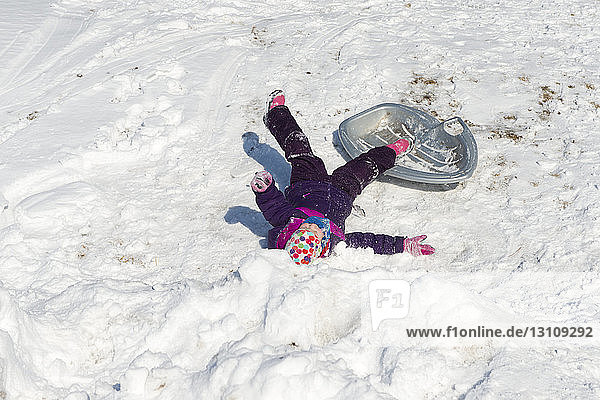 High angle view of girl lying on snow covered field