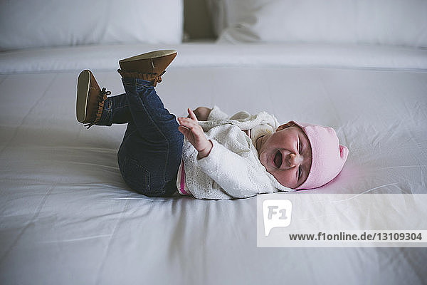 Cheerful baby laughing while lying on bed at home