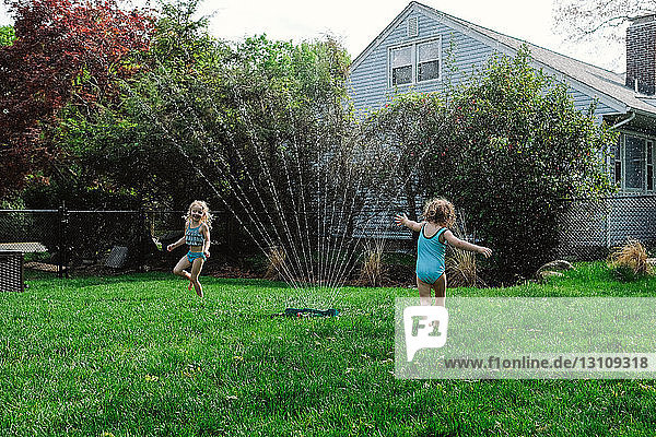 Mädchen spielen mit Wasserspritzen auf dem Rasen