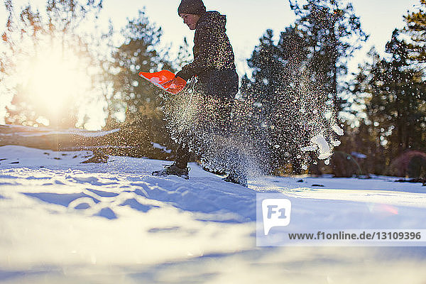 Niedrigwinkelansicht eines Mädchens  das auf dem Feld Schnee mit einer Schaufel räumt